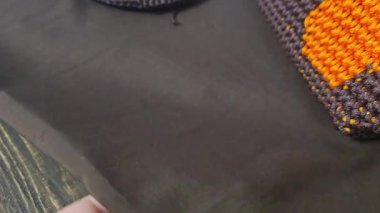 Çantanın elementleri kahverengi ve turuncu kablodan örülmüş. Tahta bir üste. El yapımı.