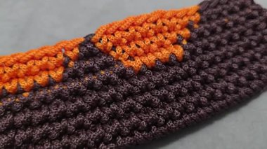 Çantanın elementleri kahverengi ve turuncu kablodan örülmüş. Tahta bir üste. El yapımı.