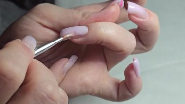 Usta tırnak uzatma yapıyor. Manikür. Çivi düzeltme. Eller ön planda. Salon servisi