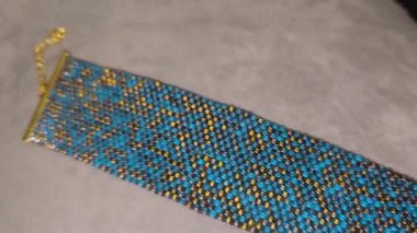 Turkuaz bilezik, altın kaplama boncuklar ve hafif arka plan. El yapımı. Evde dekorasyon ve mücevher. Boncuklardan dokuma.