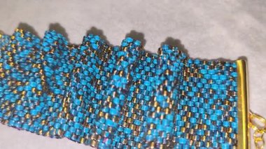 Turkuaz bilezik, altın kaplama boncuklar ve hafif arka plan. El yapımı. Evde dekorasyon ve mücevher. Boncuklardan dokuma.