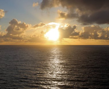  Aydınlatılmış bulutlar ve sakin denizle dramatik gün batımı