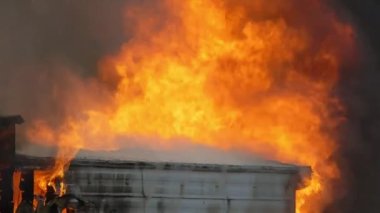 A house engulfed in flames during the day. Slow motion footage of a large trailer fire. Close up shot of a large building fire. High quality FullHD footage. Slow motion.