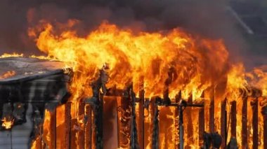 Small home engulfed in flames with a large fire. Slow motion footage of large flames. Fire and smoke billowing out of a trailer home. High quality FullHD footage. Slow motion.