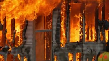 Large house fire ablaze with dangerous flames. Close up slow motion shot of a building on fire. High quality FullHD footage. Slow motion.