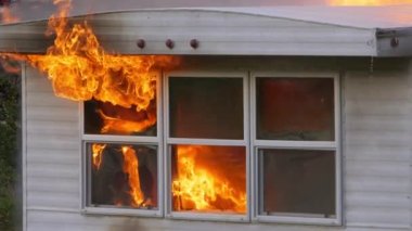 Fire and smoke rising out of windows while glass shatters and falls to the ground. Slow motion footage of a trailer home on fire. High quality FullHD footage. Slow motion.