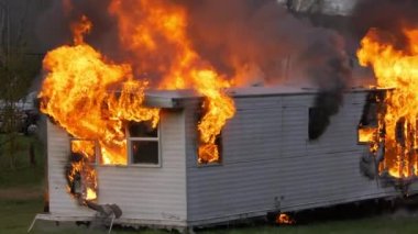 Epic slow motion shot of a trailer home on fire. House engulfed in flames with fire and smoke rising out of the windows. High quality FullHD footage. Slow motion.