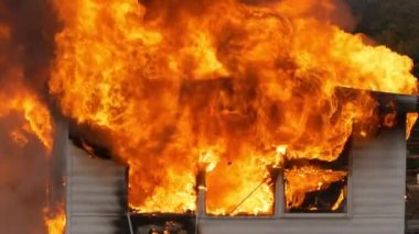 Hot flames rising as a small building is destroyed by a large fire. Slow motion footage of a small house on fire. High quality FullHD footage. Slow motion.
