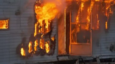 Epic shot of a trailer home on fire. House engulfed in flames with fire and smoke rising out of the door and windows. High quality 4K footage.