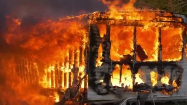 Super slow motion footage of massive flames burning a trailer home. Large house fire ablaze with large flames, falling debris, and smoke. High quality FullHD footage. Slow motion.