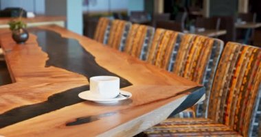 Coffee espresso cup sitting on an empty bar top in a nice restaurant. Custom made live edge bar top with black epoxy. Slow panning shot of an empty bar at a fancy restaurant. . High quality 4k footage