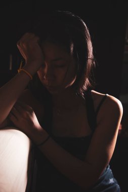 Üzgün Asyalı bir kız depresyon geçiriyor ve yatak odasının yanında tek başına oturuyor. cinsel taciz kavramı ve kadınlara yönelik şiddet, Asyalı kadın sağlığı kavramı tasarımı