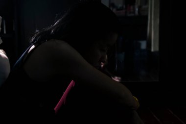 Bir Asyalı yatak odasında siluet ve üzgün bir kadın yalnız oturuyor, kalbi kırık Asyalı bir kız, yakın çekim ve arka ışık manzarası.