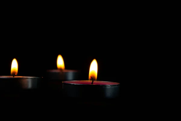 Three candles lighting and candle with yellow flame in the dark, a Light of candle in the dark.