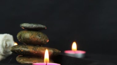 Two burning wax candles, with small stones in the dark use for relaxing time and yoga elements.