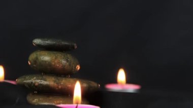 Two burning wax candles, with small stones in the dark use for relaxing time and yoga elements.