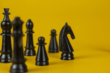 Yarışmada başarılı olan siyah satranç figürleri. Sarı arka planda strateji, yönetim veya liderlik kavramı