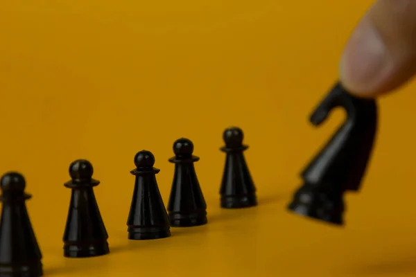 stock image A black horse Chess standing for facing to the team and fighting the problem on business on  isolated yellow background, used for success