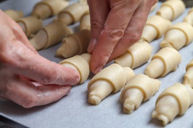 Pasta şefinin elleri hamuru daha fazla kruvasan pişirmek için rulo dolduruyor. Meyveli reçelli Fransız mini kruvasanı. Kapatın. Ev yapımı pişirme konsepti