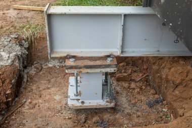 Concrete foundations support metal columns. The house's base is built on a concrete foundation with metal columns