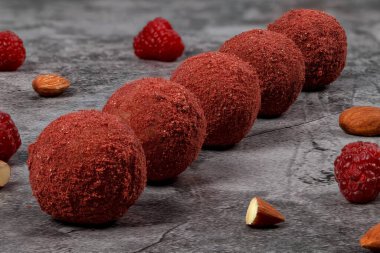 Ev yapımı yer mantarı. Yuvarlak şekerler. Yer mantarı ve badem. Gri arka planda badem ve ahududu dolu vejetaryen trüf.