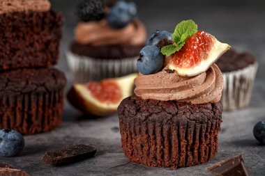 Çikolatalı kekler. Yabanmersini inciri. Kremalı kek, yabanmersini, incir ve koyu arkaplanda taze nane.