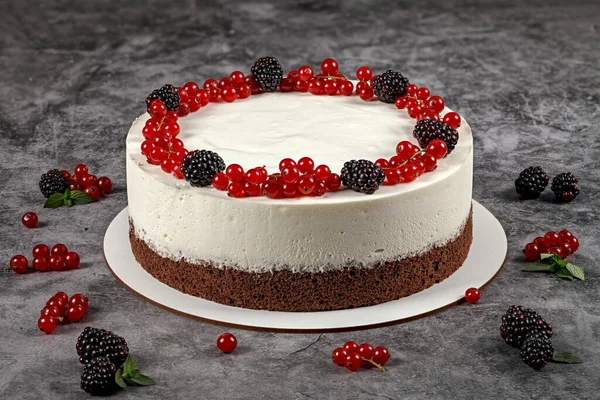 Whipped cream dessert. Cake with whipped cream and fresh red currant and blackberry on a gray background