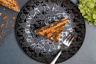 Koyu arkaplanda çikolatalı fındıklı kek. Siyah tabakta bir dilim kek. Düz yatıyordu