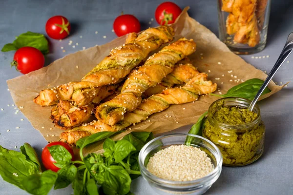 Bread sticks with sesame and tomato with pesto sauce. Homemade bread sticks. Home baking appetizers. Light background