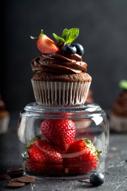 Çikolatalı kekler. Taze yabanmersinli, çilekli ve koyu arkaplanlı taze ev yapımı kekler. Ev yapımı pişirme konsepti. Yumuşak odak