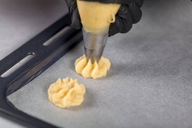 Siyah Eldivenler 'de, bir şekerci kurabiye yapmak için hamur torbasını sıkar.