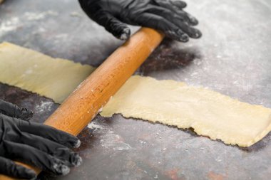 Hamur hazırlığı. Şekerci hamuru ahşap bir oklava ile yuvarlıyor.