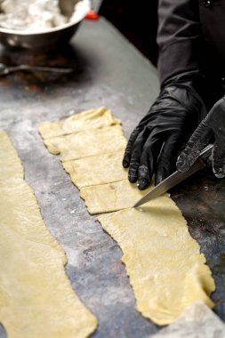 Simitler için hamur kesme işlemi. Şekerci puf böreğini bıçakla keser.