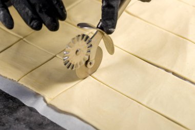 Hamur kesme işlemi. Şekerci patenli bıçakla böreği kesiyor.