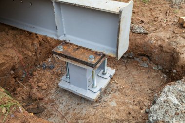 Beton temeller metal sütunları destekler. Evin temeli için beton bir temele sütunlar monte edilmiştir.