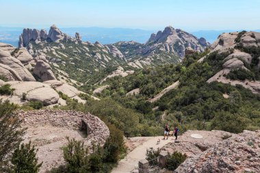 MONTSERRAT, SPAIN - 15 Mayıs 2017: Köpekleriyle tanımlanamayan yürüyüşçüler Montserrat 'ın tuhaf yamaçlarında yürüyüş parkuruna tırmanırlar.