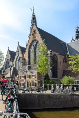 AMSTERDAM, NETHERLANDS -  MAY 5, 2013: This is a view of the apse of the old Gothic Oudekerk church from the bridge over the canal.