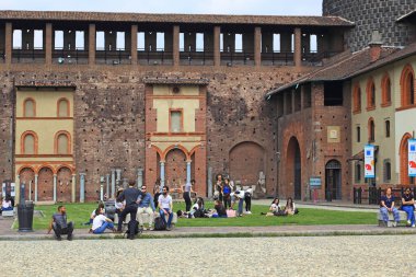 MILAN, ITALY - MAY 10, 2018: A group of unidentified youths are relaxing in the historic courtyard of the Sforza Castle.