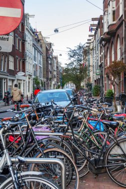 AMSTERDAM, NETHERLANDS - MAY 4, 2013: This is a parking lot for cars and bicycles on one of the old streets in the city center in the evening.