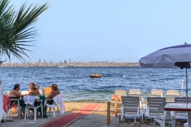 KINALIADA, TURKEY - 15 Eylül 2017: Kimliği belirsiz insanlar İstanbul 'un Asya kıyılarının karşısındaki Marmara Denizi sahilinde dinleniyor.