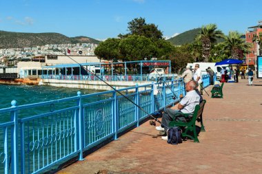 KUSADASI, TURKEY - 2 Haziran 2021: Tanımlanamayan yerliler şehrin limanında balık tutuyor.