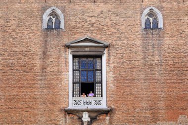 Venedik, İtalya - 18 Mayıs 2018 'de Doge Sarayı' nın avlusundaki tuğla cephedeki devasa pencerelerden birinde kimliği belirsiz turistler görülüyor..