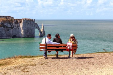 ETRETAT, FRANCE - 1 SEPTEMBER 2019: Bu bir grup tanımlanamayan tatilci Alabaster Sahili kıyılarına bakan bir uçurumun kenarındaki bankta.