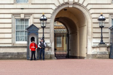 LONDON, GREAT BRITAIN - 17 Mayıs 2014: Buckingham Sarayı 'nın kapılarından biri kraliyet muhafızları ve polis tarafından çifte koruma altında.