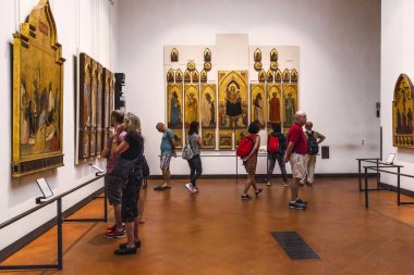 FLORENCE, İtalya - 18 Eylül 2018: Tanımlanamayan ziyaretçiler Uffizi Galerisi 'nin salonlarından birinde antik bir dini tabloyu inceliyorlar.
