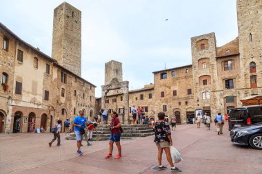 SAN GIMIGNANO, İtalya - 17 Eylül 2018: Meydanın ortasında antik bir kuyuyla ortaçağ Sarnıcı Meydanı 'nı ziyaret eden kimliği belirsiz turistler.