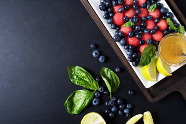 Yemek arkaplanı. Koyu arkaplanda karpuz ve bal olan yabanmersinli kahvaltı. Metin için yer