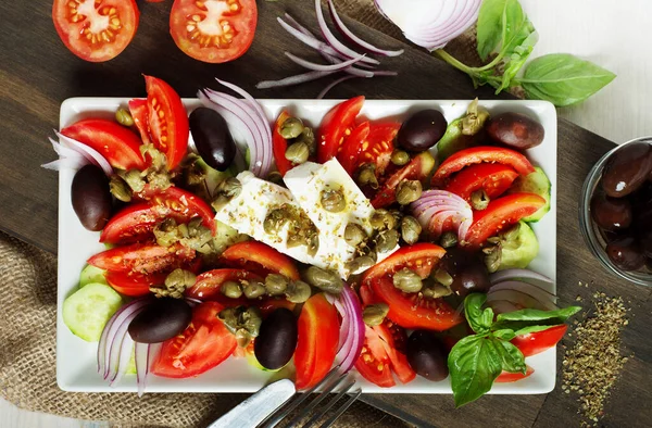 经典的希腊沙拉 西红柿 红洋葱 黄瓜和胡瓜放在长方形盘子里 免版税图库照片