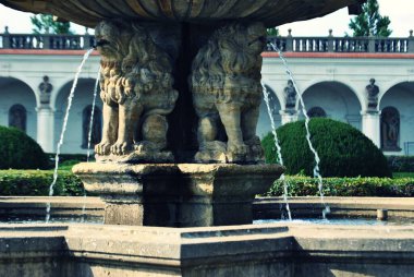 Bahçenin arka planında ağaçlar olan eski çeşmenin güzel manzarası, Kromeriz.