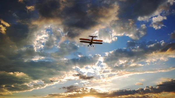 Sammansatt Ett Gult Biplan Som Flyger Mot Molnig Solnedgång Himmel Royaltyfria Stockbilder